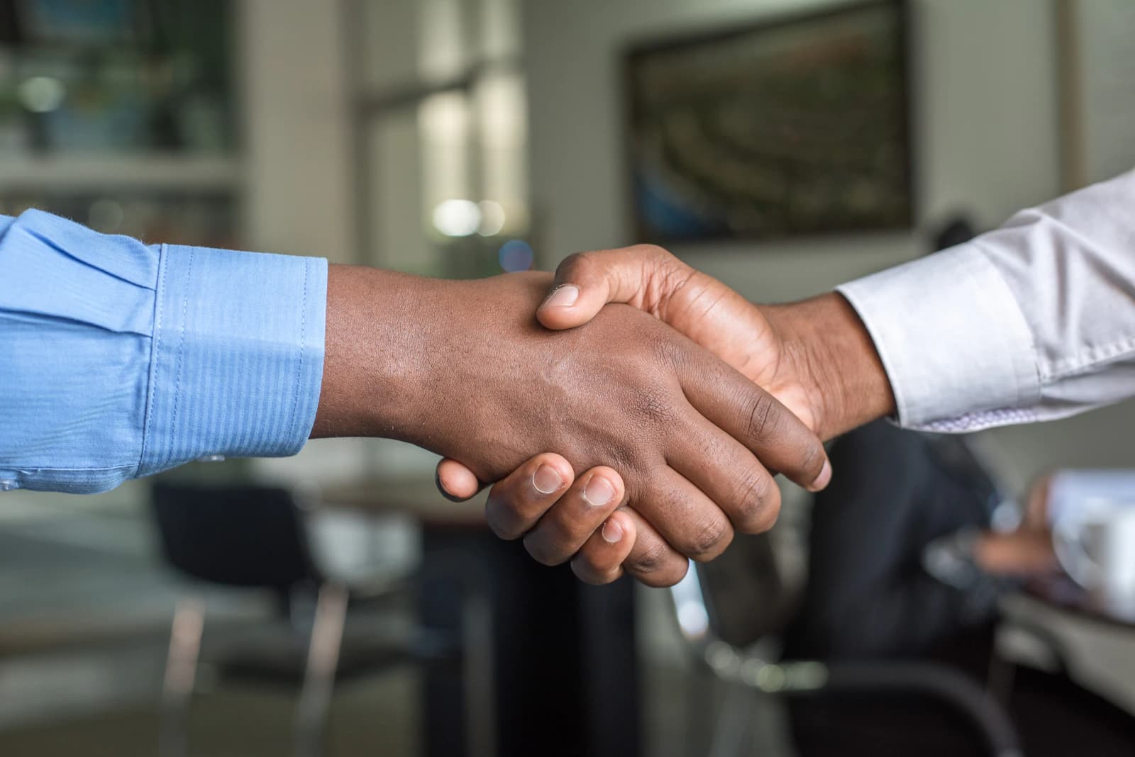 Business owner and accountant shaking hands at a meeting table with documents